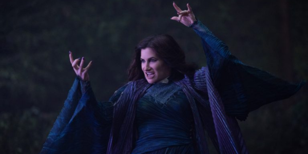 A white woman with black hair wearing a dark blue robe holds her hands in an attack.