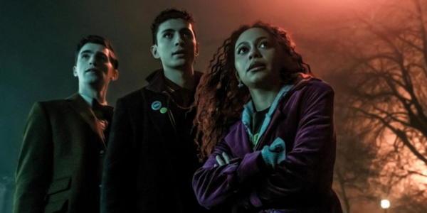 Two young men, one in 1920s clothing and the other in 1980s clothing, and a young woman stand