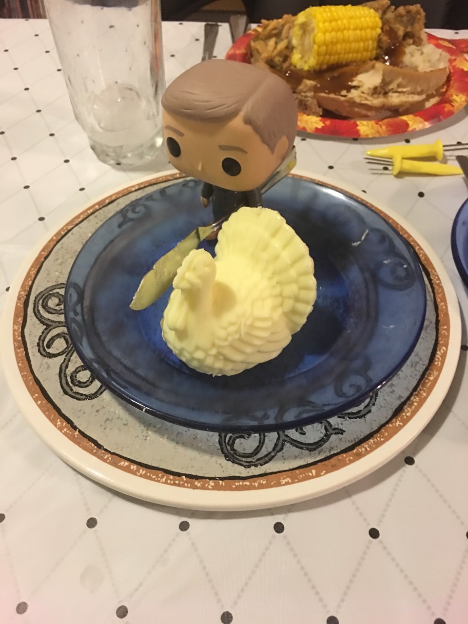 a photo of a John Watson Funko pop, holding a butter knife and standing next to a turkey-shaped thing of butter