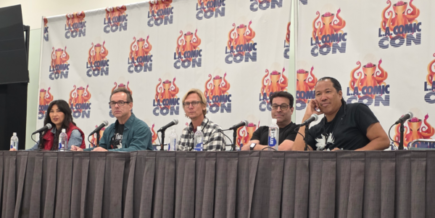 five people sitting at a table, the LA Comic Con logo on banners behind them