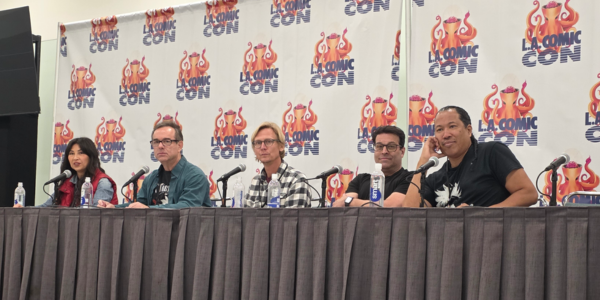 five people sitting at a table, the LA Comic Con logo on banners behind them