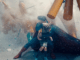 a scene of Superman protecting a small child as the world around them is engulfed in an explosion.