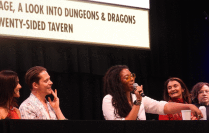 a group of five people sitting behind a table at a con; three women, one man, and one nonbinary.