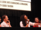 a group of five people sitting behind a table at a con; three women, one man, and one nonbinary.
