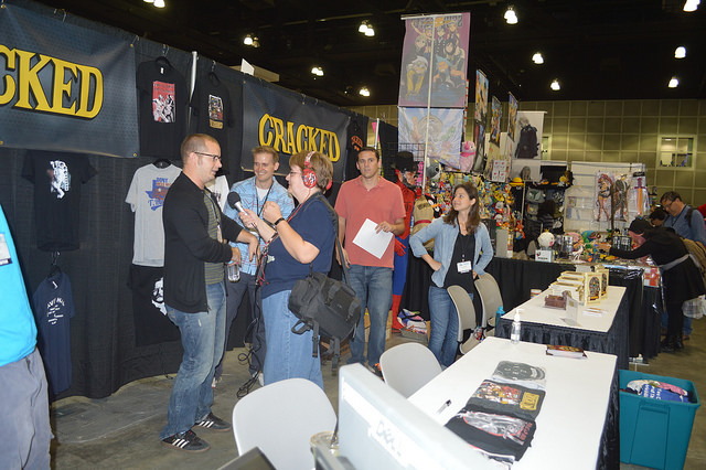 a photo from Comikaze of Angie, wearing sound equipment, talking to Dan O'Brien at Cracked's booth